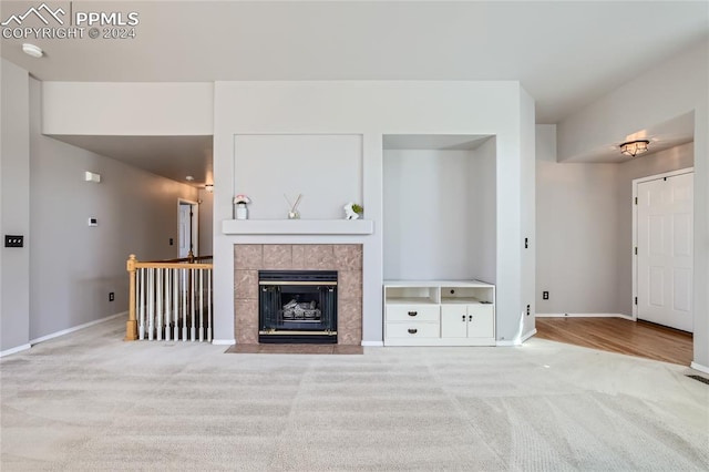 unfurnished living room featuring a tile fireplace and light carpet