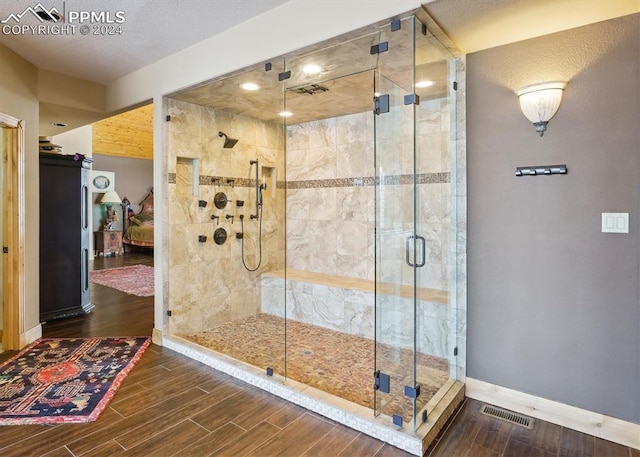 bathroom featuring hardwood / wood-style floors, a shower with shower door, and a textured ceiling