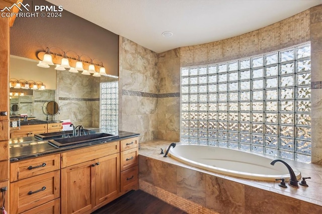 bathroom with vanity, tile walls, and tiled bath