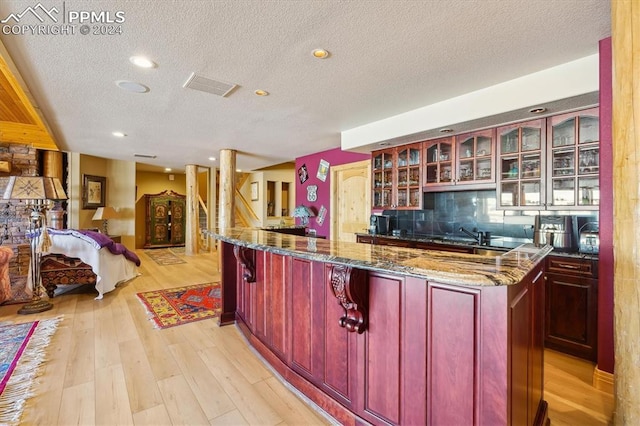 kitchen featuring a kitchen bar, backsplash, light hardwood / wood-style flooring, and a textured ceiling