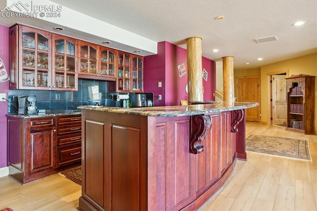 kitchen featuring decorative backsplash, a kitchen island, light hardwood / wood-style floors, and a textured ceiling