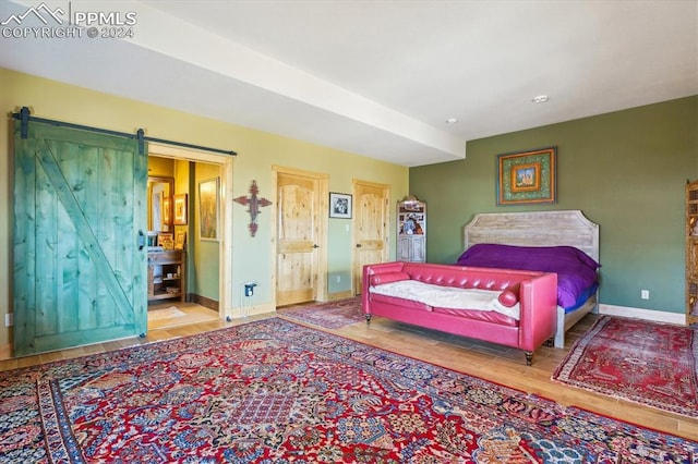 bedroom with a barn door and hardwood / wood-style flooring