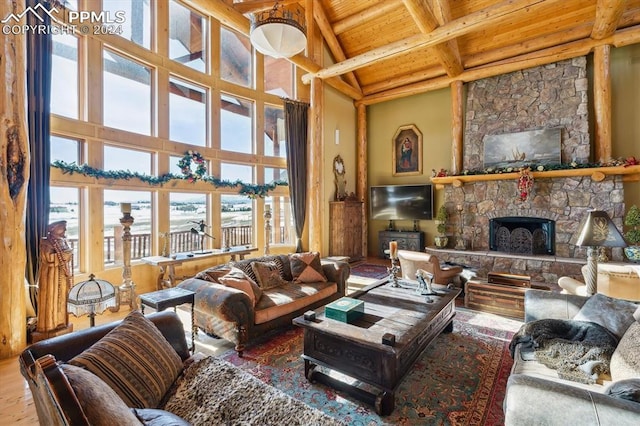 living room with a stone fireplace, plenty of natural light, beamed ceiling, and wooden ceiling