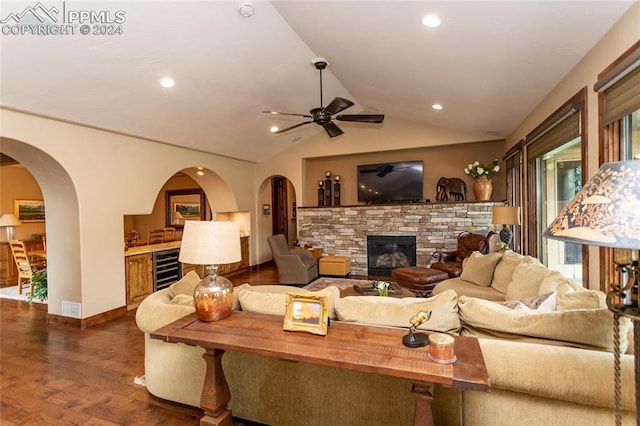 living room with ceiling fan, beverage cooler, a stone fireplace, dark hardwood / wood-style floors, and lofted ceiling