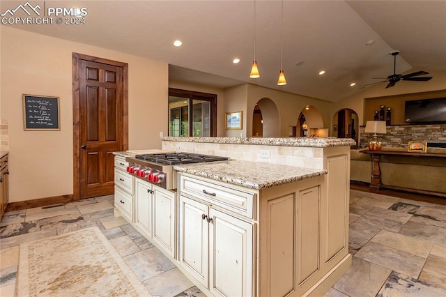 kitchen featuring tasteful backsplash, pendant lighting, a kitchen island, stainless steel gas stovetop, and lofted ceiling