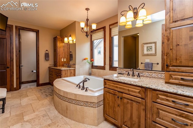 bathroom with a chandelier, vanity, and tiled tub