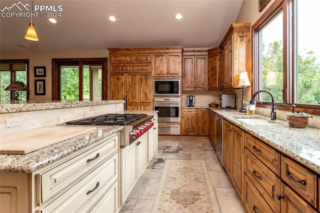 kitchen featuring light stone countertops, sink, stainless steel appliances, backsplash, and pendant lighting