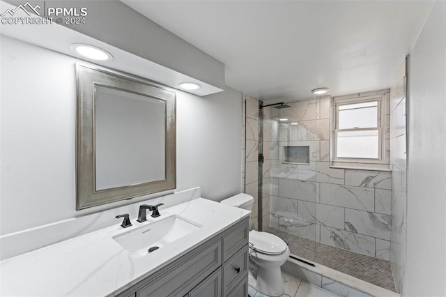 bathroom featuring tiled shower, vanity, and toilet