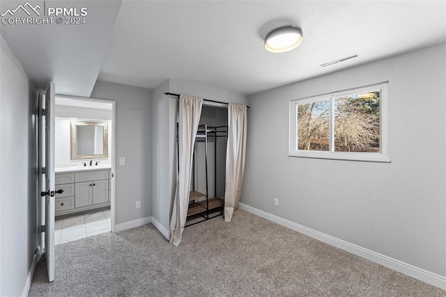 unfurnished bedroom with light colored carpet, sink, and connected bathroom