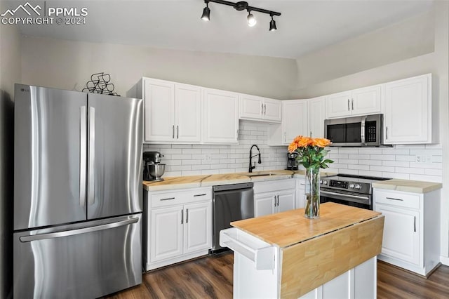 kitchen featuring white cabinets, sink, vaulted ceiling, appliances with stainless steel finishes, and tasteful backsplash