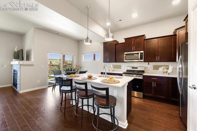 kitchen featuring sink, hanging light fixtures, stainless steel appliances, dark hardwood / wood-style flooring, and an island with sink