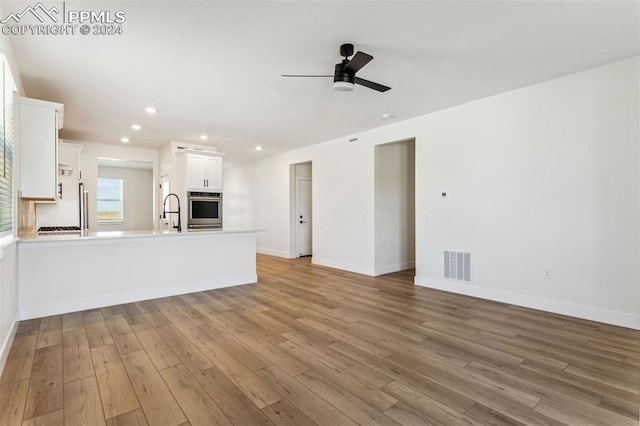 unfurnished living room featuring ceiling fan, sink, and light hardwood / wood-style flooring