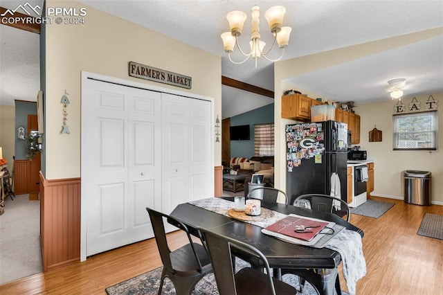 dining area with vaulted ceiling, light hardwood / wood-style flooring, a chandelier, and a textured ceiling