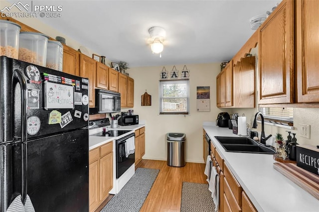 kitchen featuring black appliances, light hardwood / wood-style floors, and sink