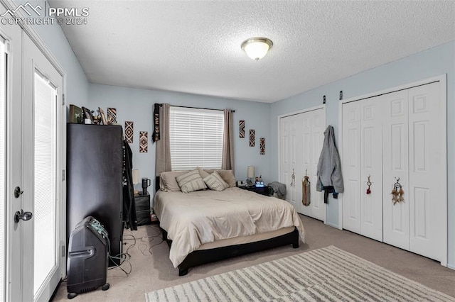 carpeted bedroom with a textured ceiling and two closets