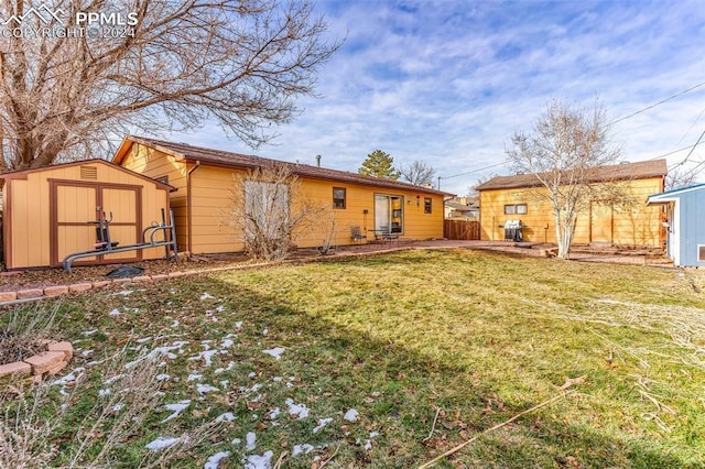 rear view of house featuring a storage shed and a lawn