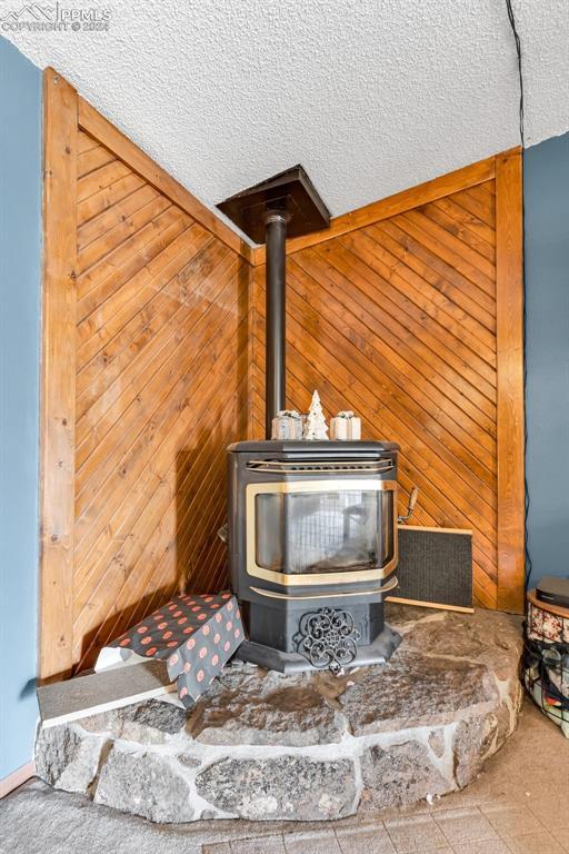 room details with a wood stove, wood walls, and a textured ceiling