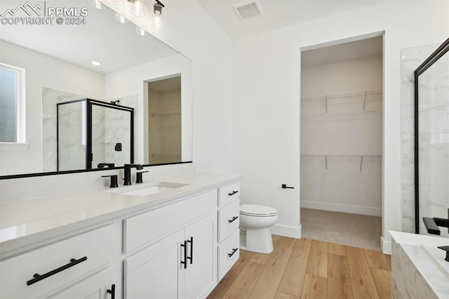 bathroom with hardwood / wood-style floors, vanity, toilet, and a shower with shower door