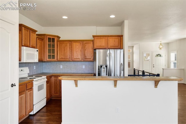 kitchen featuring a breakfast bar, white appliances, dark hardwood / wood-style floors, and a kitchen island