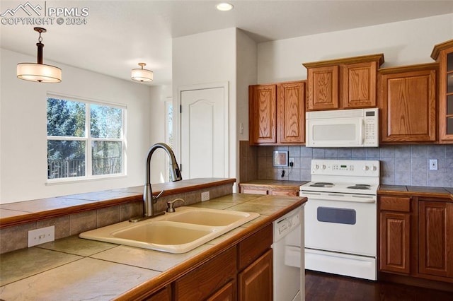 kitchen with tile countertops, sink, hanging light fixtures, and white appliances