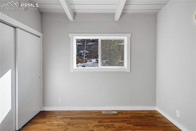 spare room with beam ceiling and hardwood / wood-style floors