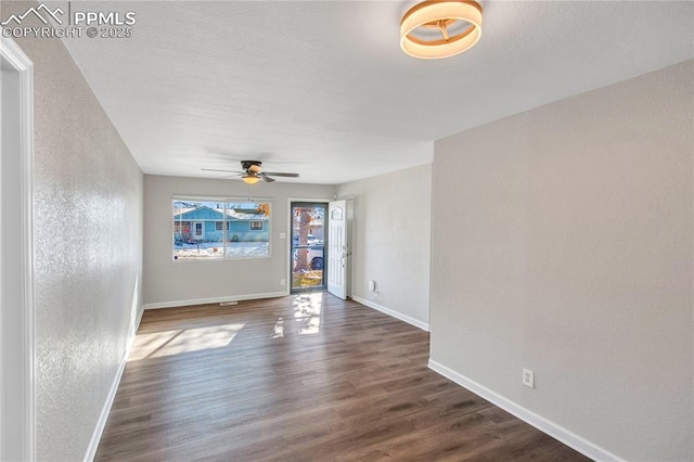 empty room with ceiling fan and dark hardwood / wood-style flooring