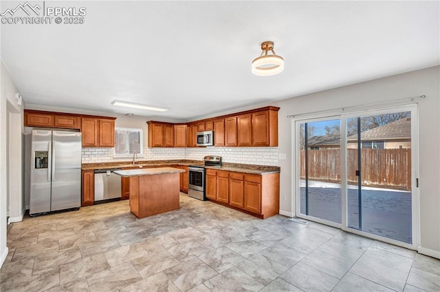 kitchen featuring light stone countertops, stainless steel appliances, tasteful backsplash, a kitchen island, and sink