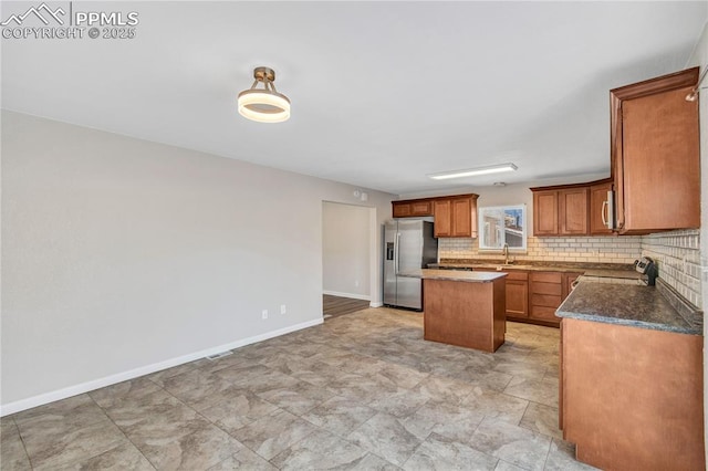 kitchen with decorative backsplash, a kitchen island, appliances with stainless steel finishes, dark stone countertops, and sink