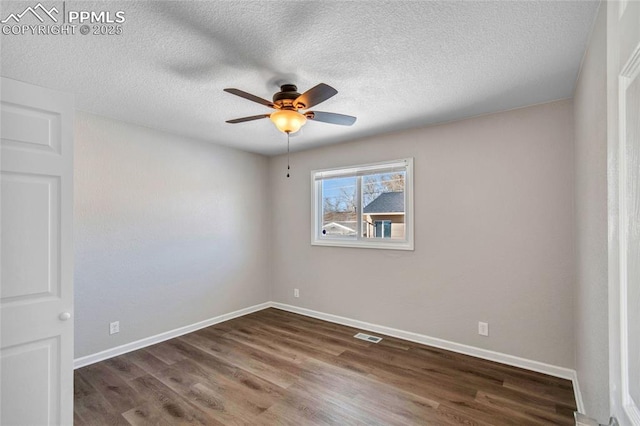 empty room featuring dark wood-type flooring, a textured ceiling, and ceiling fan