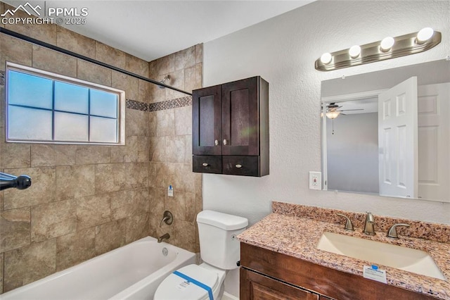 full bathroom with ceiling fan, toilet, vanity, and tiled shower / bath