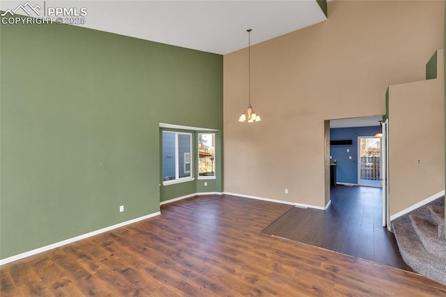 unfurnished room featuring a notable chandelier, dark wood-type flooring, and a high ceiling