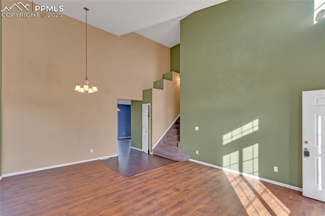 spare room with dark hardwood / wood-style flooring, high vaulted ceiling, and a chandelier