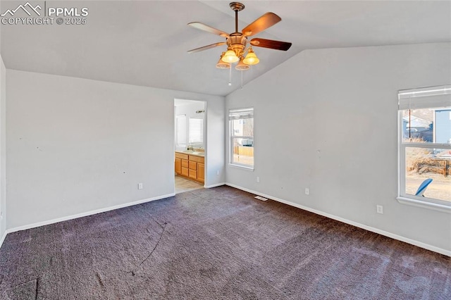 unfurnished bedroom featuring carpet, ceiling fan, ensuite bath, and vaulted ceiling