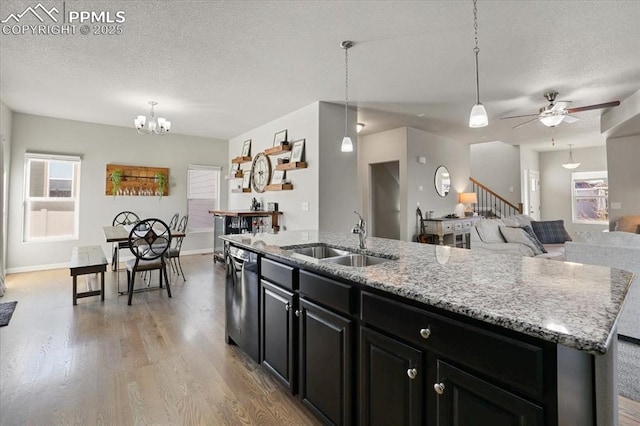 kitchen featuring pendant lighting, stainless steel dishwasher, a kitchen island with sink, and sink