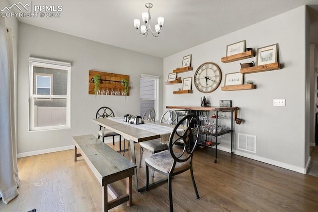 dining area featuring hardwood / wood-style floors and an inviting chandelier