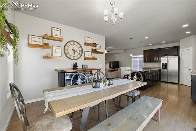 dining space featuring sink, ceiling fan with notable chandelier, and dark hardwood / wood-style floors