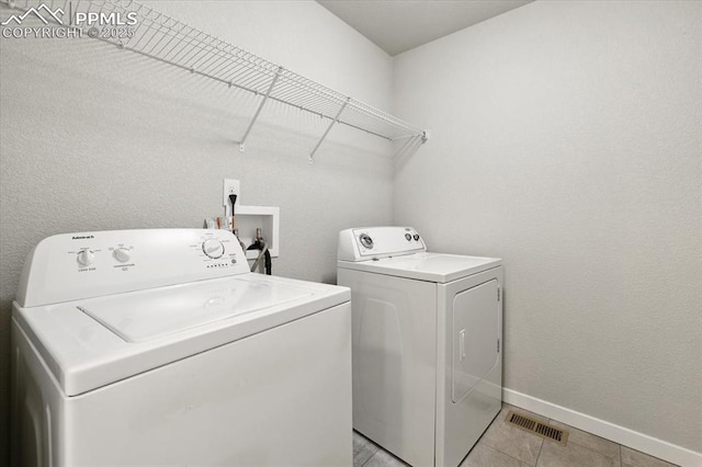 laundry room featuring washing machine and clothes dryer and light tile patterned floors