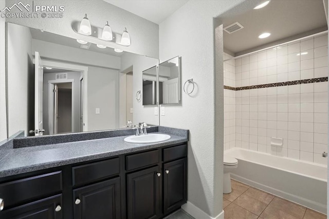 full bathroom featuring tile patterned floors, tiled shower / bath, vanity, and toilet