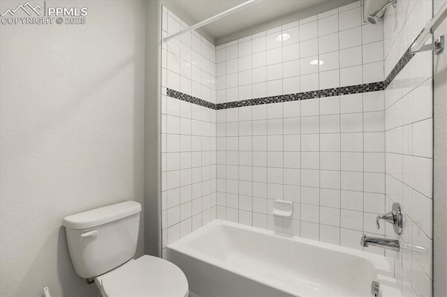 bathroom featuring tiled shower / bath combo and toilet