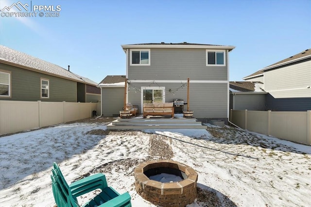 snow covered rear of property with a fire pit and a wooden deck