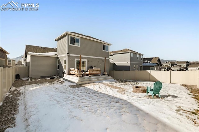 snow covered rear of property with a deck and an outdoor fire pit