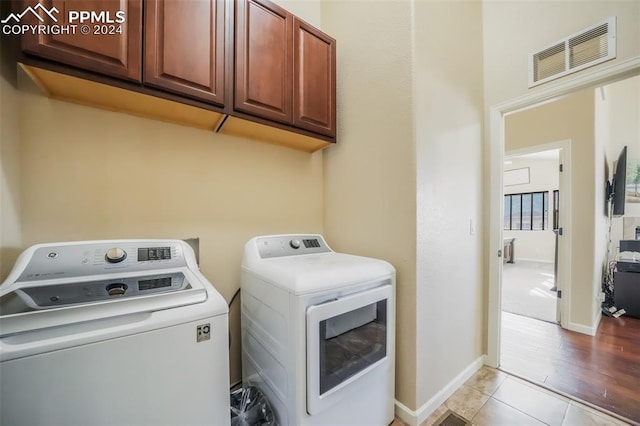 laundry area featuring cabinets, independent washer and dryer, and tile patterned floors