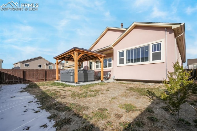 rear view of property featuring a hot tub