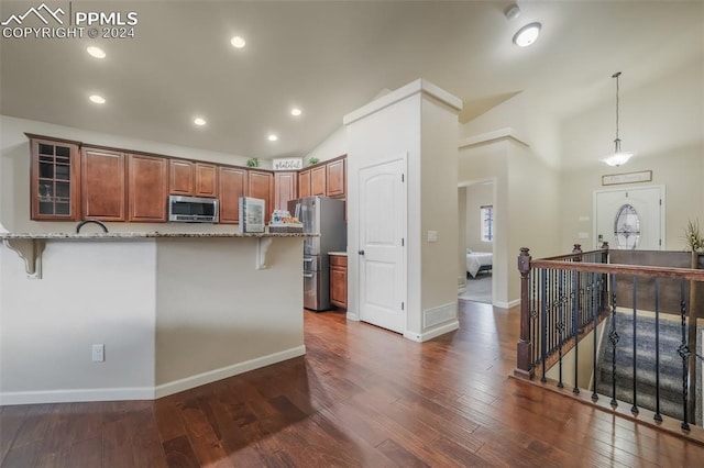 kitchen with light stone counters, a breakfast bar, pendant lighting, and appliances with stainless steel finishes