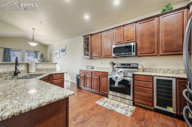 kitchen with sink, light wood-type flooring, appliances with stainless steel finishes, decorative light fixtures, and beverage cooler