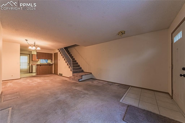 carpeted foyer featuring a notable chandelier and a textured ceiling