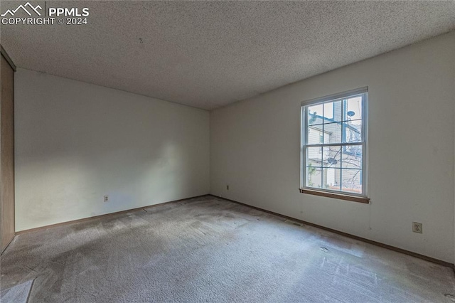 carpeted spare room with a textured ceiling