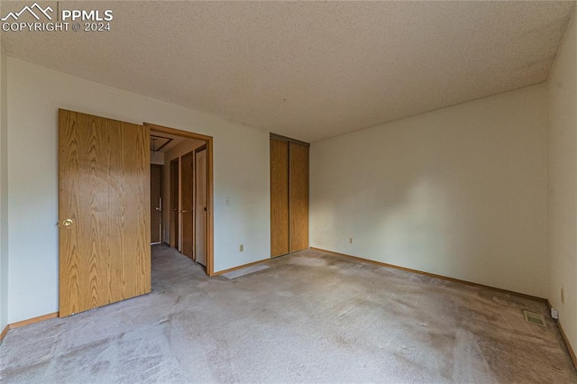 spare room featuring light carpet and a textured ceiling