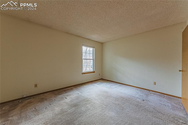 carpeted empty room featuring a textured ceiling