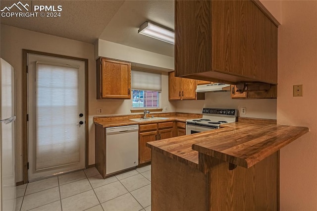 kitchen featuring sink, wooden counters, kitchen peninsula, white appliances, and light tile patterned floors